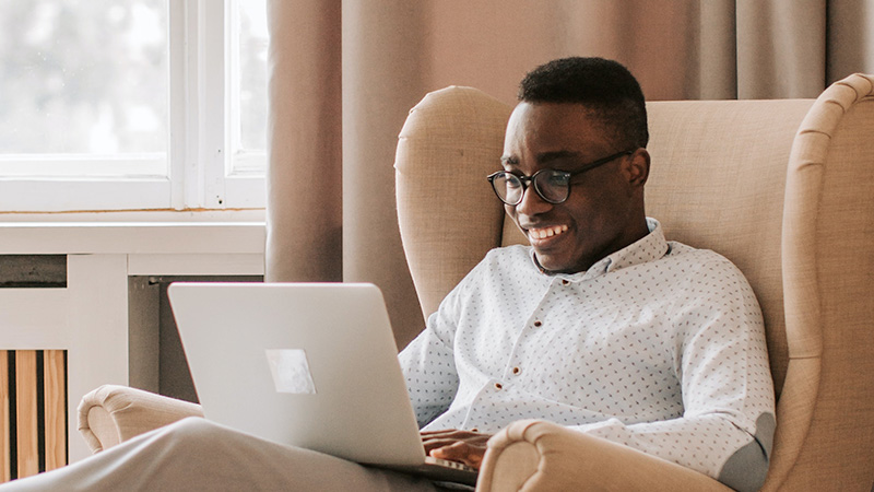 Man sitting on chair looking at laptop computer screen