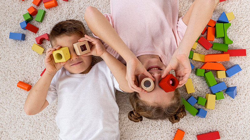 Kids lying on floor palying with wooden blocks